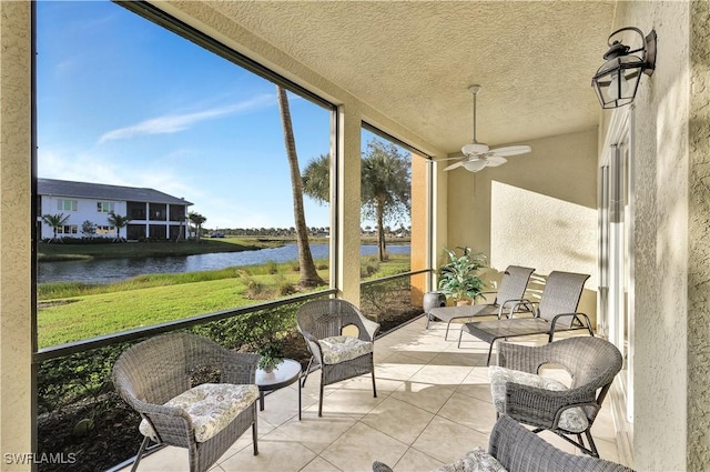 sunroom featuring ceiling fan and a water view