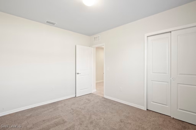 unfurnished bedroom with light carpet and a closet