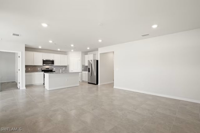 kitchen with light tile patterned flooring, white cabinetry, an island with sink, stainless steel appliances, and decorative backsplash