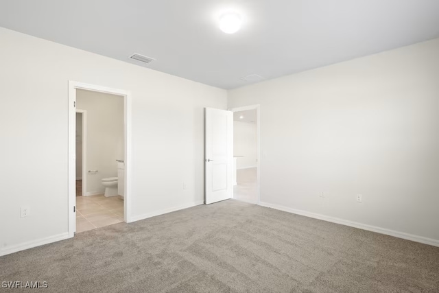 unfurnished bedroom with light colored carpet and ensuite bath