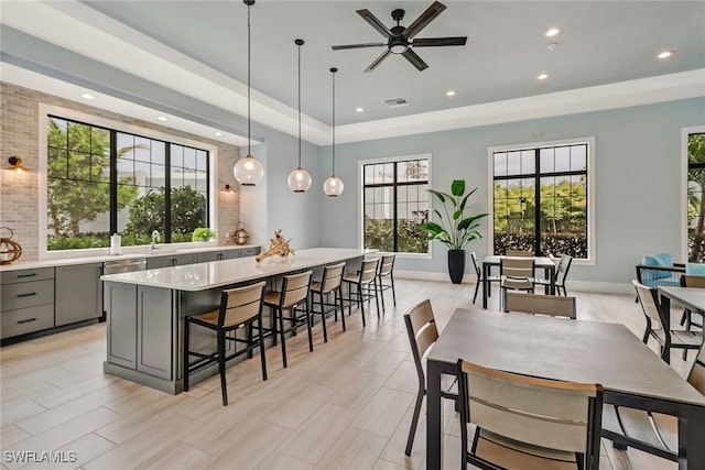 kitchen with gray cabinets, hanging light fixtures, a healthy amount of sunlight, and a spacious island