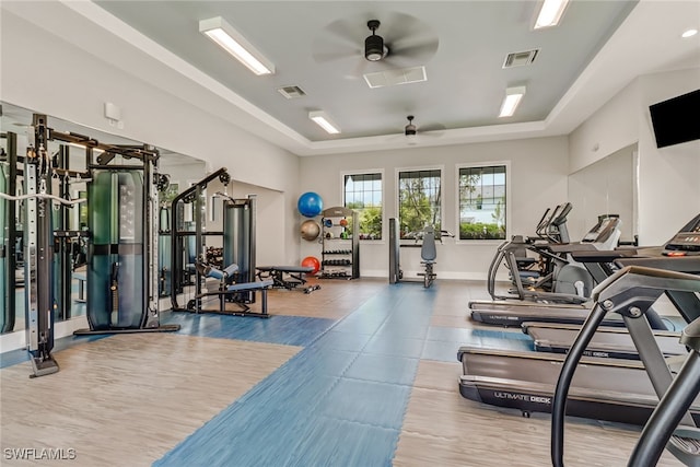 workout area featuring a raised ceiling and ceiling fan