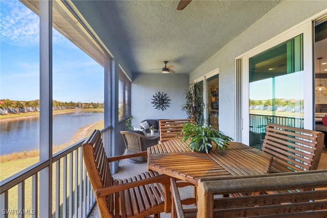 sunroom / solarium with ceiling fan and a water view