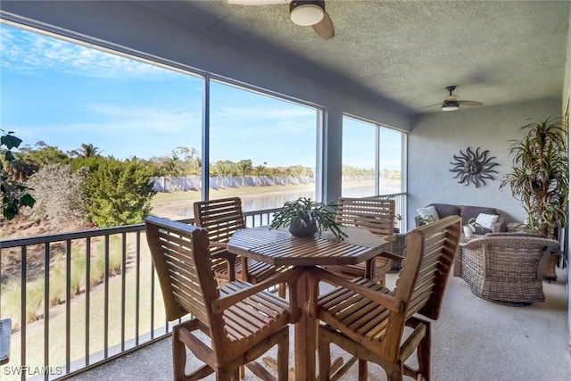 sunroom / solarium featuring ceiling fan and a water view