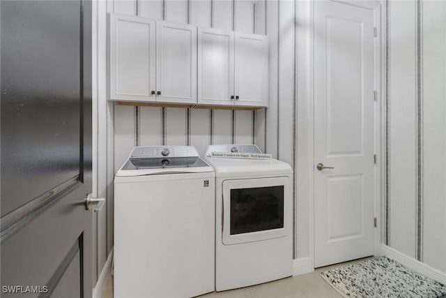 washroom featuring cabinets, washing machine and clothes dryer, and light tile patterned floors