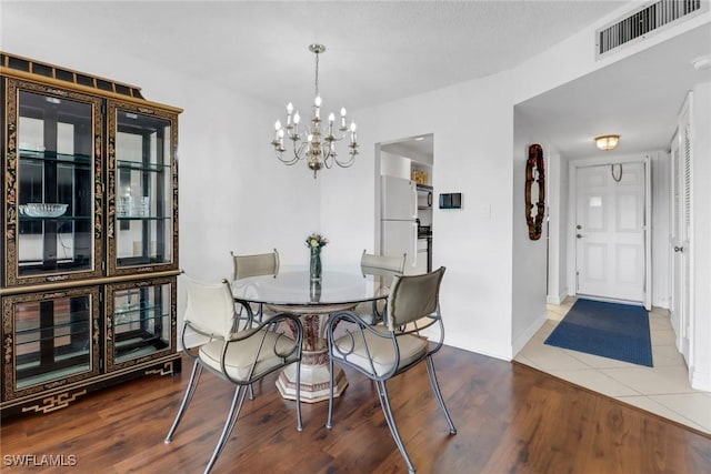 dining space with visible vents, baseboards, an inviting chandelier, and wood finished floors