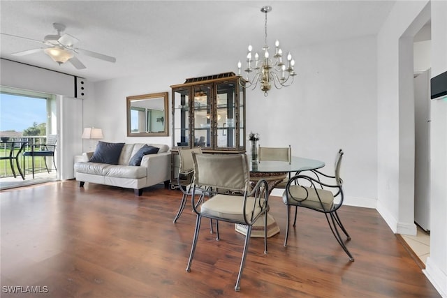 dining space featuring ceiling fan with notable chandelier, baseboards, and wood finished floors