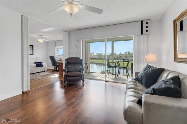 living area with wood finished floors, a ceiling fan, and a healthy amount of sunlight