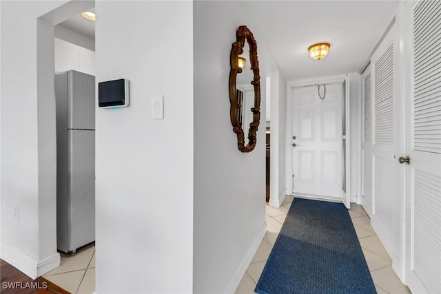 corridor with baseboards and light tile patterned floors