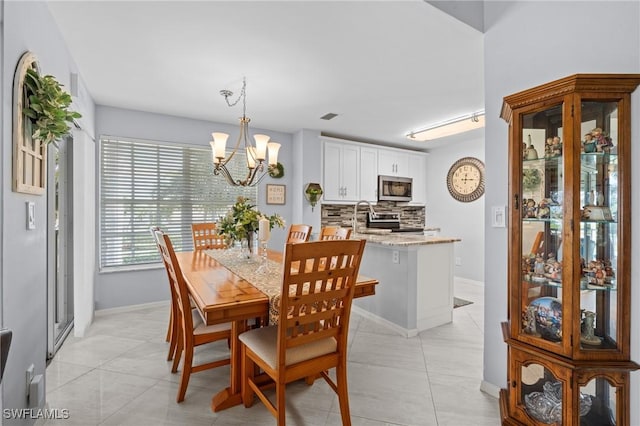 dining space featuring sink, light tile patterned flooring, and an inviting chandelier