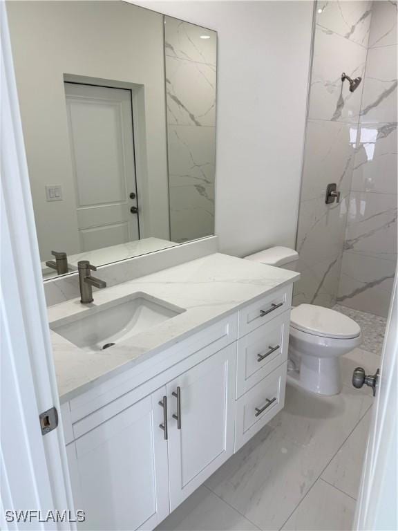 bathroom with a tile shower, vanity, and toilet