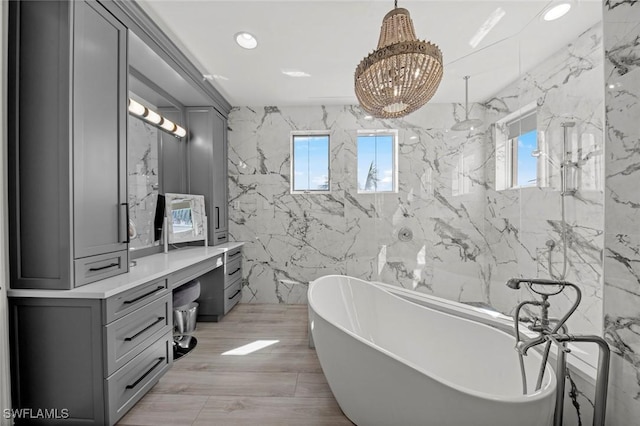 bathroom with a washtub, vanity, a chandelier, and tile walls