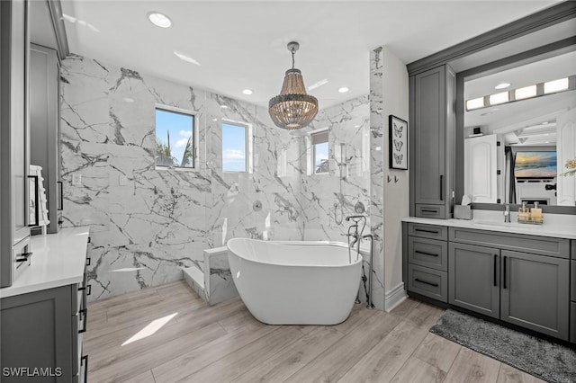 bathroom with vanity, a bath, hardwood / wood-style floors, and tile walls