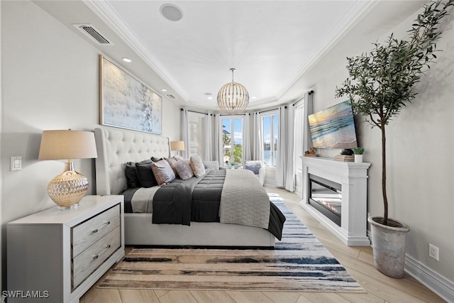 bedroom featuring crown molding, light wood-type flooring, and a tray ceiling