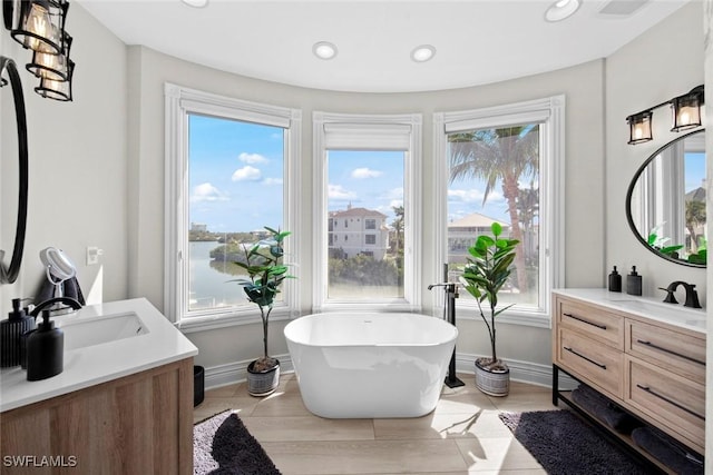 bathroom with hardwood / wood-style flooring, a healthy amount of sunlight, vanity, and a bathtub