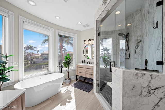 bathroom with independent shower and bath, vanity, and hardwood / wood-style floors