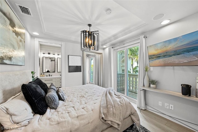 bedroom featuring a tray ceiling, access to exterior, ensuite bath, and hardwood / wood-style flooring