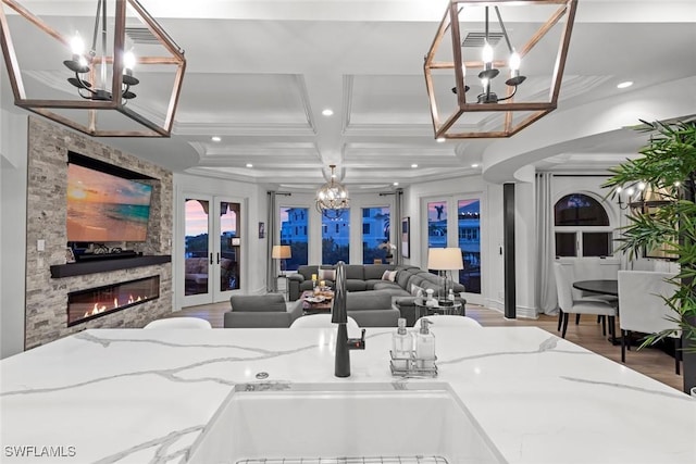 living room with wood-type flooring, sink, coffered ceiling, a notable chandelier, and french doors