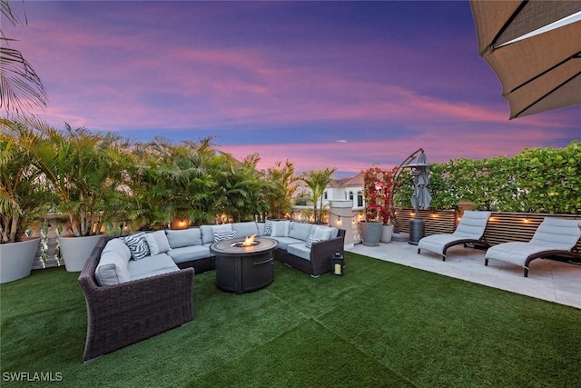 patio terrace at dusk with an outdoor living space with a fire pit and a lawn