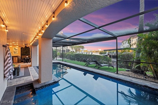 pool at dusk featuring a lanai and a patio area