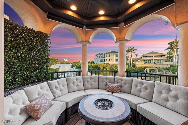 patio terrace at dusk with a balcony and an outdoor living space with a fire pit