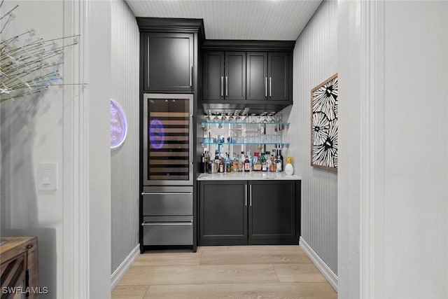 bar with wine cooler and light hardwood / wood-style floors