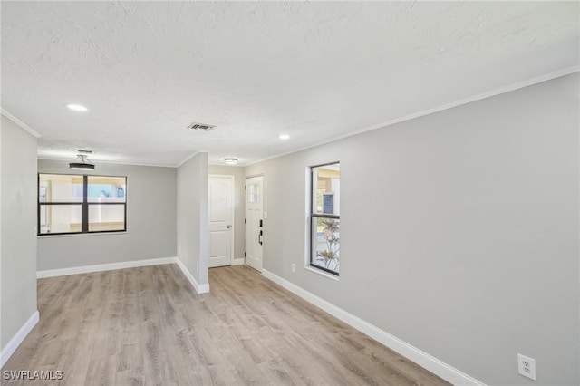 empty room with ornamental molding, a textured ceiling, and light hardwood / wood-style flooring