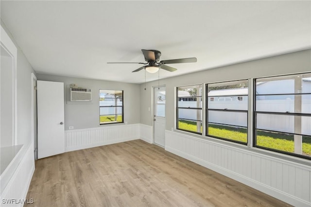 unfurnished room with a wall mounted air conditioner, ceiling fan, and light hardwood / wood-style floors