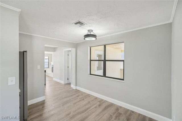 empty room featuring crown molding, a textured ceiling, and light wood-type flooring