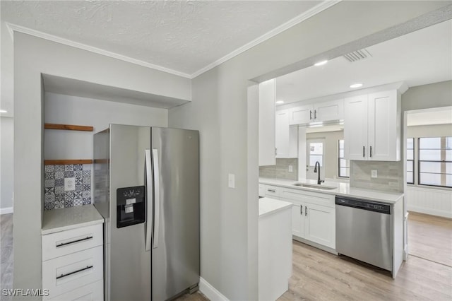 kitchen with sink, white cabinetry, light hardwood / wood-style flooring, appliances with stainless steel finishes, and backsplash