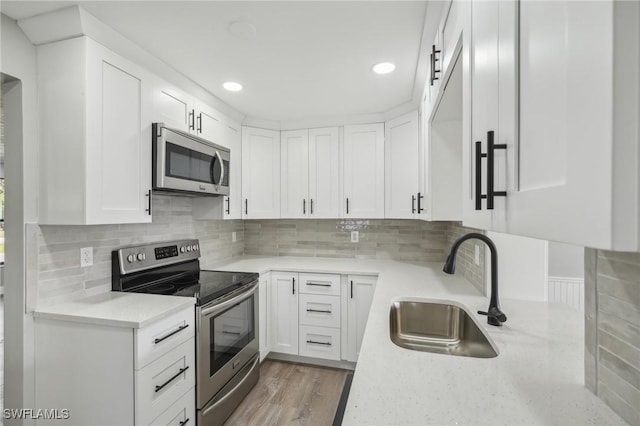 kitchen with light stone counters, stainless steel appliances, sink, and white cabinets