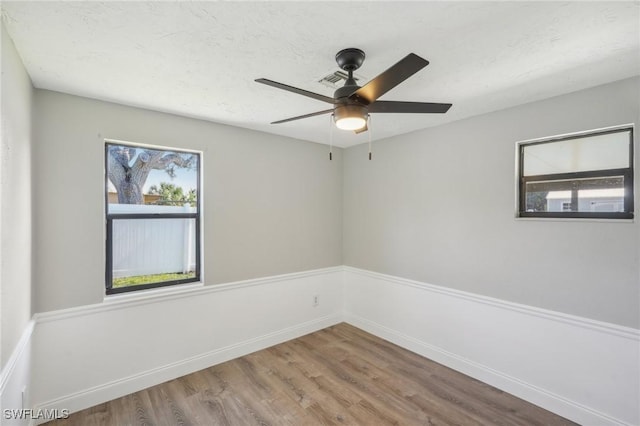 empty room with ceiling fan, a healthy amount of sunlight, and hardwood / wood-style floors