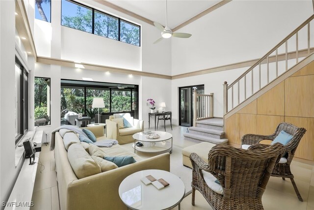 tiled living room featuring ceiling fan, a healthy amount of sunlight, and a towering ceiling