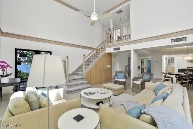 living area featuring visible vents, ceiling fan, a high ceiling, and stairs