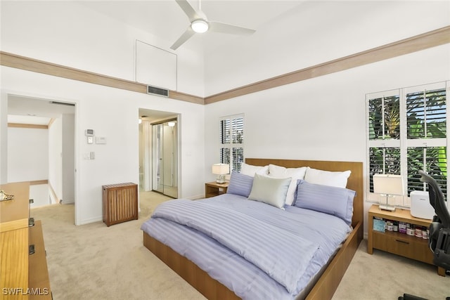 bedroom featuring visible vents, baseboards, light colored carpet, a towering ceiling, and ceiling fan