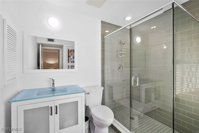 bathroom with an enclosed shower, vanity, and toilet