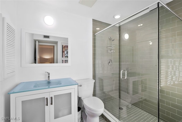 bathroom featuring toilet, a stall shower, visible vents, and vanity