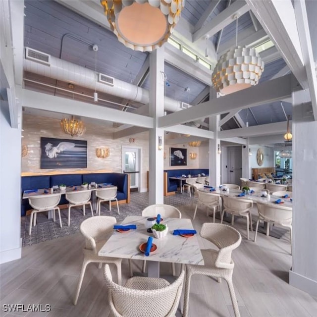 dining room with beamed ceiling, a towering ceiling, and hardwood / wood-style floors