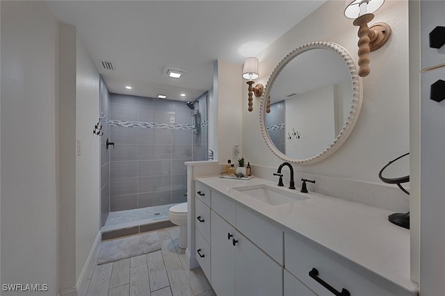 bathroom with vanity, toilet, and a tile shower