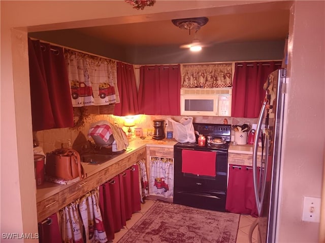 kitchen with stainless steel fridge, light tile patterned flooring, and electric range