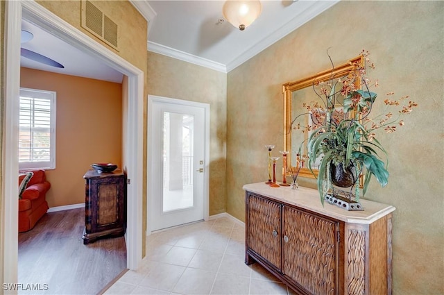 entryway with light tile patterned floors, visible vents, crown molding, and baseboards