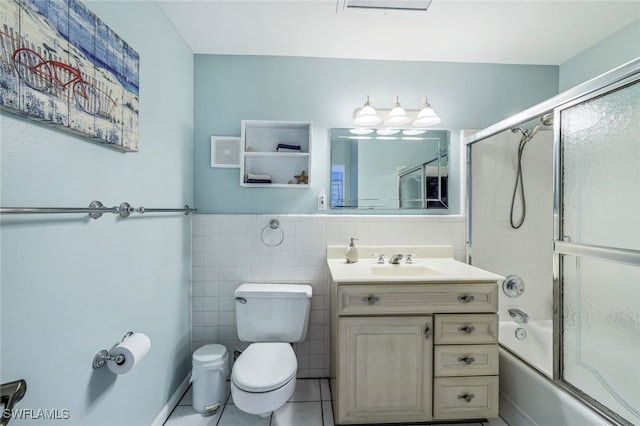 full bathroom featuring tile patterned floors, toilet, combined bath / shower with glass door, tile walls, and vanity