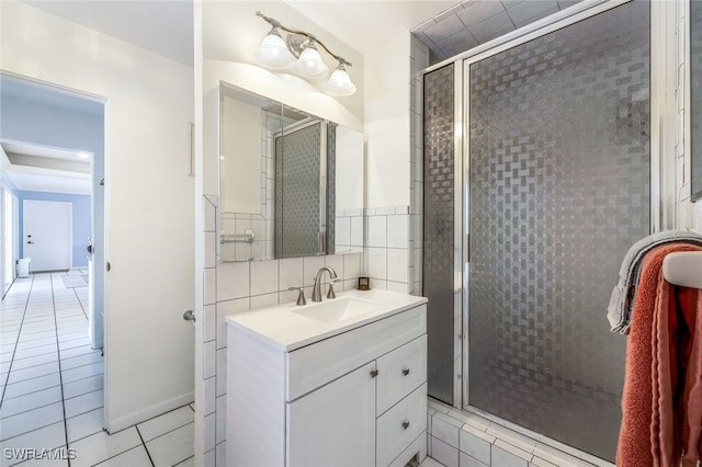 bathroom with vanity, a shower with shower door, tile patterned flooring, and tile walls