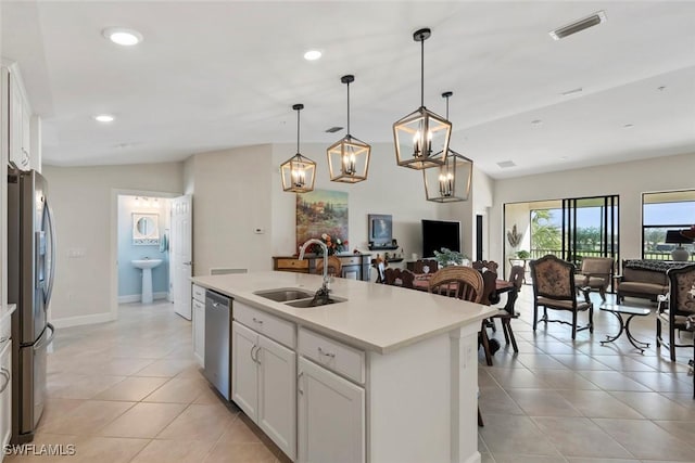 kitchen featuring sink, a center island with sink, pendant lighting, stainless steel appliances, and white cabinets