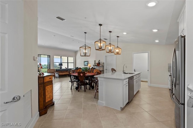 kitchen featuring sink, an island with sink, pendant lighting, stainless steel appliances, and white cabinets