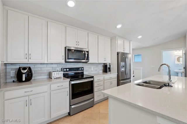 kitchen featuring lofted ceiling, sink, white cabinetry, stainless steel appliances, and decorative backsplash