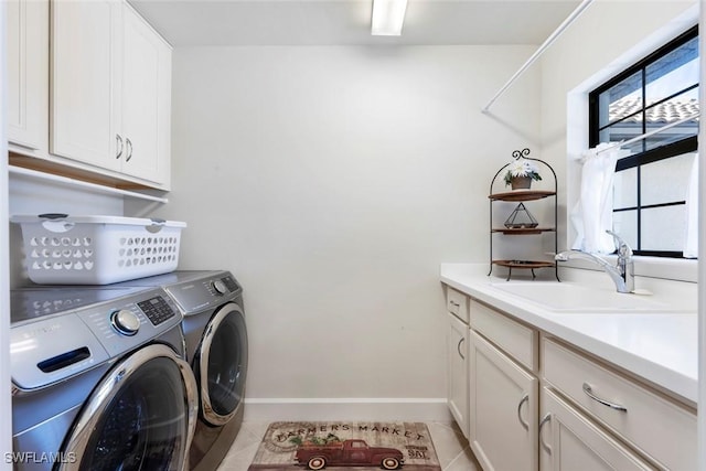 laundry area with sink, light tile patterned floors, washing machine and dryer, and cabinets