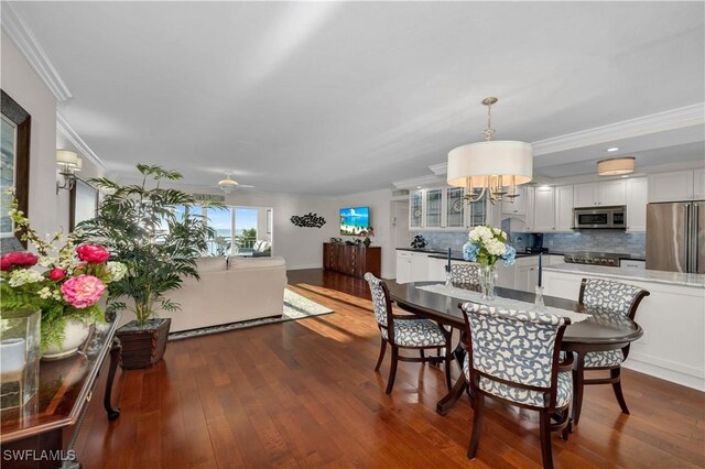 dining space featuring dark wood-type flooring, ceiling fan, and crown molding