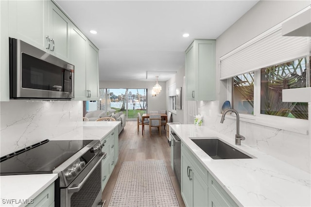 kitchen with light stone countertops, appliances with stainless steel finishes, sink, and decorative backsplash