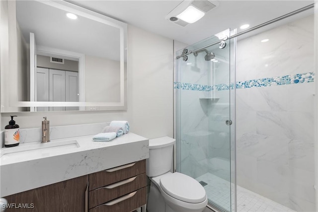 bathroom featuring vanity, a shower with shower door, and toilet